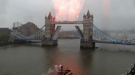 Lors de la procession sur la Tamise, c'est un feu d'artifice tir&eacute; depuis le Tower bridge qui a salu&eacute; le passage du bateau royal. (IAN KINGTON / AFP)