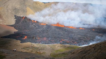 Des curieux viennent contempler la mer de lave qui s'échappe d'une fissure volcanique, le 3 août 2022 à Grindavik (Islande). (JEREMIE RICHARD / AFP)