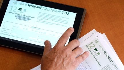 Un homme consulte sa d&eacute;claration d'imp&ocirc;t de solidarit&eacute; sur la fortune sur sa tablette, le 19 juillet 2012 &agrave; Rennes.&nbsp; (DAMIEN MEYER / AFP)