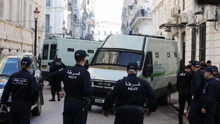 Des policiers devant le véhicule qui a amené les deux ex-Premiers ministres alégiens à leur procès à Alger, le 2 décembre 2019.&nbsp; (BILLAL BENSALEM / AFP)