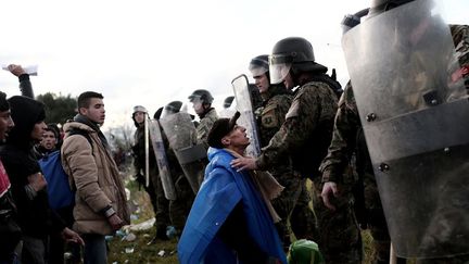 26 novembre 2015. Près d’Idomeni à la frontière gréco-macédonienne, un migrant s’agenouille devant des policiers macédoniens après avoir franchi la frontière grecque. La Macédoine, comme de nombreux pays européens, a imposé des restrictions au passage de sa frontière. La foule criait aux policiers «ouvrez la frontière!».   (ANGELOS TZORTZINIS / AFP)