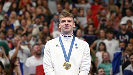 Léon Marchand sur le podium après son titre olympique sur 200 m papillon, le 31 juillet 2024 à la Paris La Défense Arena, à Nanterre (Hauts-de-Seine). (JONATHAN NACKSTRAND / AFP)