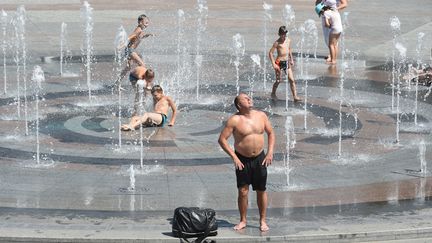 Un homme et des enfants se rafraîchissent, dans le centre de Kiev (Ukraine), le 3 août 2018 (SERGEI SUPINSKY / AFP)