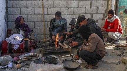 Une famille prépare un repas dans les ruines de sa maison à Rafah, dans le sud de la bande de Gaza, le 13 janvier 2024 (- / AFP)