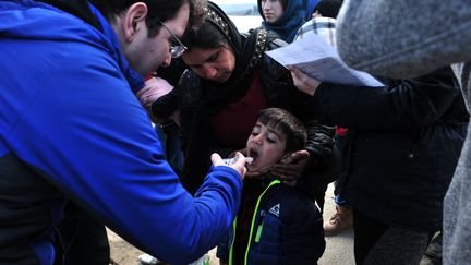 Un médecin suédois donne un sirop à un enfant malade. "Nous essayons au maximum de soigner les migrants mais à cause de leur conditions de vie, il y en a beaucoup qui sont malades. On a même eu deux cas de pneumonie", déplore l'humanitaire.&nbsp; (SAKIS MITROLIDIS / AFP)