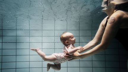 Une femme nage avec son b&eacute;b&eacute; dans une piscine au Danemark, en d&eacute;cembre 2011. (DAVID TROOP / BILDERBERG)