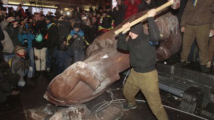 Un manifestant frappe avec une masse la statue de L&eacute;nine &agrave; Kiev (Ukraine), le 8 d&eacute;cembre 2013. (SERGEI CHUZAVKOV / AP / SIPA)