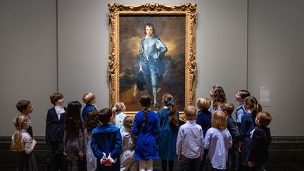 Des enfants autour du tableau&nbsp;"The Blue Boy" de Thomas Gainsborough à la National Gallery de Londres le 24 janvier 2022. (TOLGA AKMEN / AFP)