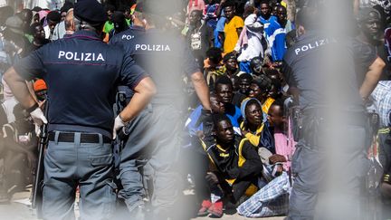 Des migrants se rassemblent devant le centre opérationnel de l'île italienne de Lampedusa, le 14 septembre 2023. (ALESSANDRO SERRANO / AFP)