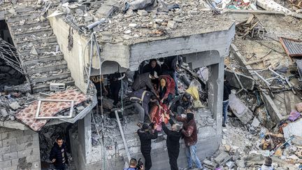 Des hommes récupèrent le corps d’une victime tuée au lendemain d’une frappe israélienne au camp de réfugiés d’Al-Maghazi le 25 décembre 2023. (MAHMUD HAMS / AFP)