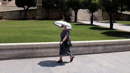 Une femme se protège d'un soleil de plomb dans le centre d'Athènes (Grèce), le 5 juillet 2023. (NIKOLAS KOKOVLIS / NURPHOTO / AFP)