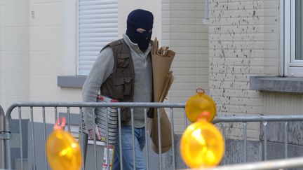 Un policier entre dans un immeuble de Bruxelles, le 16 mars 2016, au lendemain d'une opération anti-terroriste menée par les polices belge et française, dans le cadre de l'enquête sur les attentats de Paris en novembre 2015. (JOHN THYS / AFP)