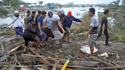 Des habitants transportent des corps après le tsunami qui a déferlé sur Palu, en Indonésie. (AP / SIPA)