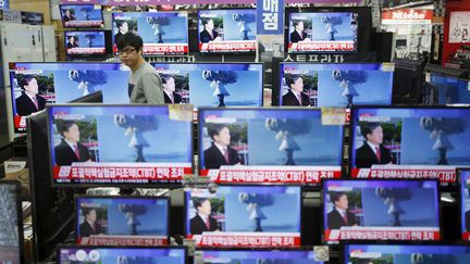 Un vendeur regarde des écrans de télévision retransmettant des images transmises par la&nbsp;Corée du Nord et montrant un possible essai nucléaire, le 6 janvier 2016 à Séoul (Corée du Sud). (KIM HONG-JI / REUTERS)