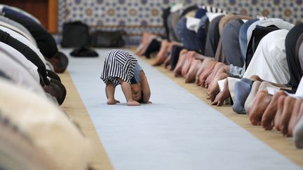 Un petit gar&ccedil;on tente d'imiter les hommes qui prient dans la Grande Mosqu&eacute;e de Strasbourg (Bas-Rhin), le 9 juillet 2013. (VINCENT KESSLER / REUTERS)