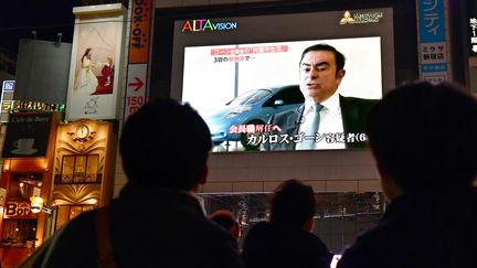 Des piétons regardent un programme d'informations consacré à&nbsp;Carlos Ghosn à Tokyo (Japon), le 22 novembre 2018. (KAZUHIRO NOGI / AFP)