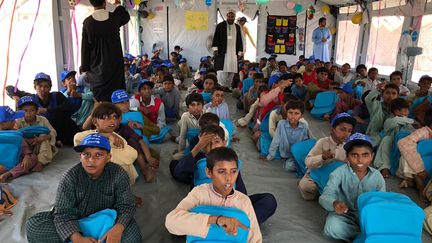 Des enfants réfugiés dans un camp de fortune&nbsp;assistent à un cours en attendant la visite du Premier ministre pakistanais Shehbaz Sharif et du Secrétaire général des Nations Unies Antonio Guterres, dans le district de Jaffarabad, au sein de la province du Balouchistan, le 10 septembre 2022. (MUHAMMAD DAUD / AFP)