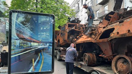 Un camion-grue dépose sur le trottoir un tank et un blindé de l’armée russe, tous deux calcinés, dans une rue de Kiev, lundi 9 mai 2022. (AGATHE MAHUET / RADIO FRANCE)