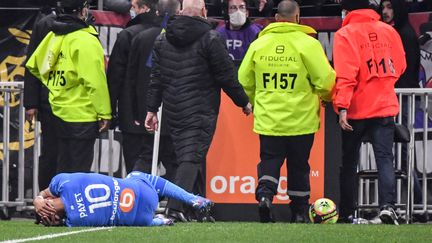 Dimitri Payet au sol après la bouteille reçue à la tête lors de la rencontre entre l'OL et l'OM, dimanche.&nbsp; (PHILIPPE DESMAZES / AFP)