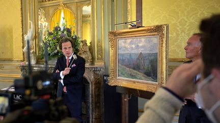 Le commissaire priseur Aymeric Rouillac au coté de la tile de Claude Monet "Dieppe" peinte en 1882, lors de sa mise en vente le 6 juin 2021 à Montbazon (Indre-et-Loire). (GUILLAUME SOUVANT / AFP)