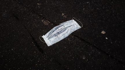 Un masque de protection, sur le sol, à Paris, le 16 mars 2020. (AMAURY CORNU / HANS LUCAS / AFP)