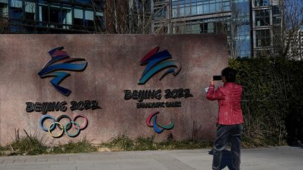 Une femme prend en photo le logodes Jeux olympiques et paralympiques d'hiver de Pékin 2022, à Pékin (Chine), le 7 décembre 2021. (NOEL CELIS / AFP)