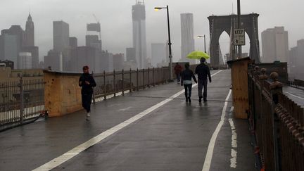 Des passants profitent mardi matin de la fermeture du c&eacute;l&egrave;bre pont de Brooklyn &agrave; la circulation et prennent la mesure de l'ampleur des d&eacute;g&acirc;ts. (SPENCER PLATT / GETTY IMAGES NORTH AMERICA / AFP)