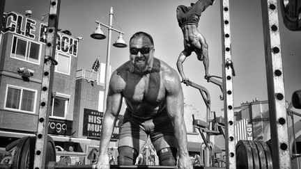 Un haltérophile lève des poids pendant qu'un culturiste réalise une figure aérienne avec les bras au Muscle Beach Gym de Venice Beach en Californie.
 (Dotan Saguy / National Geographic)