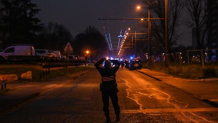 Une policière sécurise le périmètre d'intervention des secours dans le quartier du Mas du Taureau à Vaulx-en-Velin, près de Lyon (Rhône) où s'est déclaré un incendie vendredi 16 décembre 2022. (OLIVIER CHASSIGNOLE / AFP)