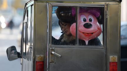 Une femme &agrave; l'arri&egrave;re d'un taxi p&eacute;kinois (Chine) en compagnie d'un ballon &agrave; l'effigie de Minnie, le 7 novembre 2013. Le premier parc d'attraction Disney en Asie devrait ouvrir &agrave; Shangha&iuml; fin 2015. (MARK RALSTON / AFP)