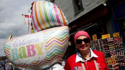 Une fan de la famille royale avec un ballon célébrant la naissance du fils&nbsp;de Meghan Markle et du prince Harry, le 6 mai 2019 près du château de Windsor (Royaume-Uni), à une quarantaine de kilomètres de Londres. (ADRIAN DENNIS / AFP)