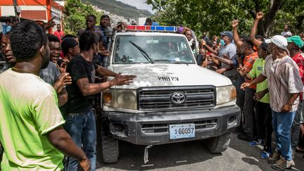 Des habitants de Port-au-Prince (Haïti) saluent le passage d'une voiture de police, le 8 juillet 2021. (VALERIE BAERISWYL / AFP)