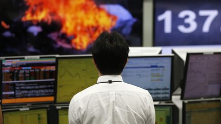 Un trader regarde &agrave; la t&eacute;l&eacute;vision, &agrave; Tokyo (Japon) les images de de l'avion du vol MH17 de la Malaysia Airlines, en train de br&ucirc;ler, vendredi 18 juillet 2014. (REUTERS)