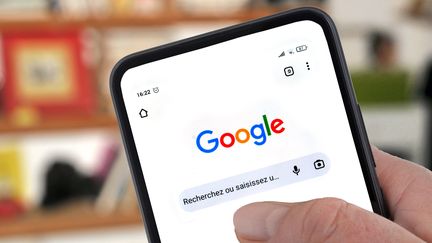 Une page d'accueil de Google sur un écran de smartphone tenu en main. (RICHARD VILLALON / MAXPPP)