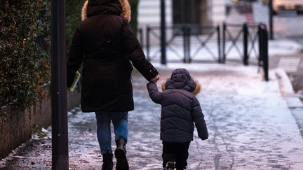 Une femme et un enfant marchent dans les rues de Mulhouse (Haut-Rhin), le 8 janvier 2023. (SEBASTIEN BOZON / AFP)