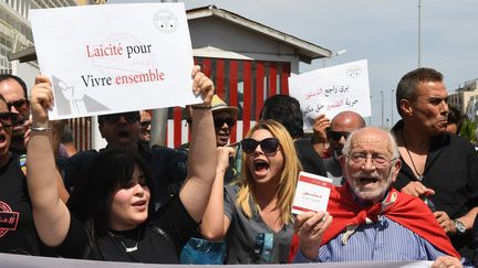 Une Tunisienne affiche une pancarte sur laquelle on peut lire : "Laïcité pour vivre ensemble" lors d'une manifestation en mai 2018&nbsp;pour dénoncer la fermeture des cafés et des restaurants pendant le mois de ramadan. (FETHI BELAID / AFP)