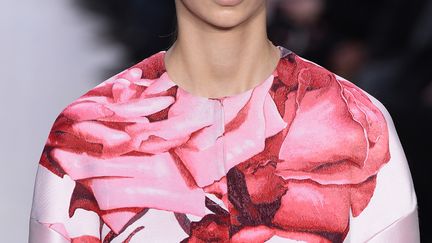 L'Italien Giambattista Valli propose d'élégantes robes, corolle ou à godet, qui s'arrêtent au-dessus du genoux. La taille est bien marquée mais les épaules sont larges. Le créateur décline ces modèles en noir, vieux rose, bordeaux (verni, pailleté), dans un rouge plus flamboyant, avec des fleurs brodées ou imprimées.... 
 (BERTRAND GUAY / AFP)