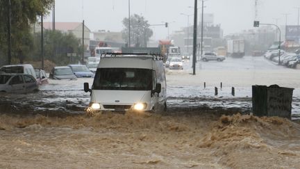 Une voiture circule au milieu d'une route inondée, sous un pont, à Héraklion (Grèce), le 15 octobre 2022. (MAXPPP)