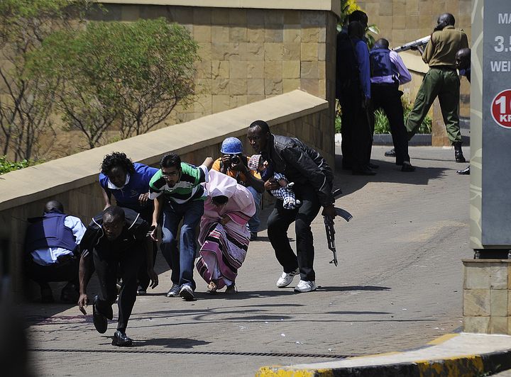 Un policier kényan tente de mettre en sécurité des&nbsp;habitants et&nbsp;un bébé après que des shebab se sont introduits dans un centre commercial à Nairobi, le 21 septembre 2013.&nbsp; (SIMON MAINA / AFP)