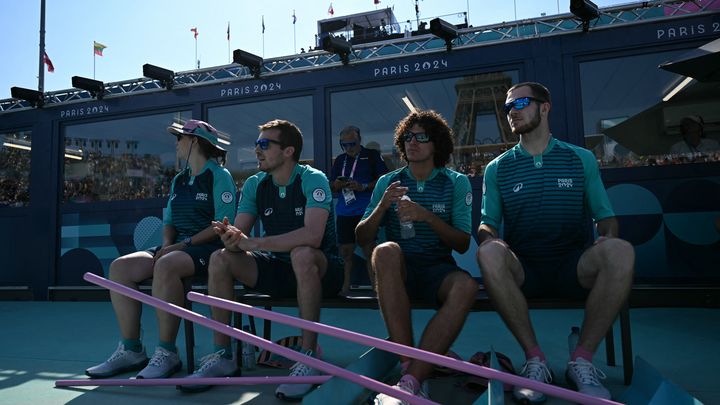 Des volontaires chargés de niveler le sable regardent le match de beach-volley opposant les Pays-Bas et l'Espagne, dans le tableau masculin des Jeux olympiques de Paris 2024, au stade de la tour Eiffel, le 29 juillet 2024. (MAURO PIMENTEL / AFP)