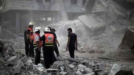 Les secours palestiniens sur les d&eacute;combres d'un b&acirc;timent bombard&eacute; par l'arm&eacute;e isra&eacute;lienne &agrave; Rafah (Gaza), le 4 ao&ucirc;t 2014. (MAHMUD HAMS / AFP)