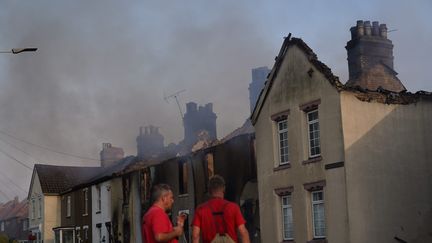 Des pompiers observent la fumée au-dessus de&nbsp;Wennington, près de Londres (Royaume-Uni), le 19 juillet 2022. (MAXPPP)