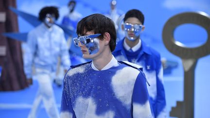 Le streetwear est mort, vive le costume ! L'Américain Virgil Abloh, star des millenials, détourne cet uniforme du vestiaire masculin et s'amuse avec pour la maison Louis Vuitton.&nbsp;Boutons dépareillés ou volants sur les manches, les costumes sont portés avec des boots à bouts pointus et bonnets de sauna, une chemise cravatée est cousue sur un manteau noir à la coupe impeccable... la collection transpire l'ironie, la nonchalance et revendique "la joie de vivre". Les couleurs fluo apparaissent par touches, en mono-boucles d'oreilles ou mitaines ou en total look rose fluo.
Une partie de la collection est à motif nuages sur un ciel bleu qui reproduit celui du décor. Alors que Virgil Abloh évoque l'"effet de serre" dans un abécédaire distribué avant son défilé,&nbsp;Sur le podium, des manteaux en vison argenté ou renard iridescent.&nbsp;Hommage à l'ADN de malletier de la maison parisienne, les sacs au logo tant convoité sont omniprésents, futuristes ou classiques, qui prennent des formes irrégulières.&nbsp;Roi du streetwear, Virgil Abloh a intrigué le mois dernier en déclarant à la surprise générale que cette tendance allait mourir.&nbsp;"Le streetwear, Virgil Abloh l'adopte ou le rejette en toute liberté", est-il expliqué dans la note d'intention du défilé.&nbsp;Désormais c'est l'évolution du costume et la révision des codes vestimentaires qui l'intéresse.&nbsp;"Le costume, symbole de la convention, du commerce et du succès est sur le point de quitter sa zone du confort. Le dress code du vieux monde est neutralisé, réapproprié au service de la joie du vivre", assure-t-il. (KRISTY SPAROW / GETTY IMAGES EUROPE)