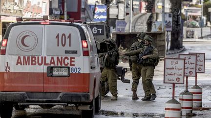 Des soldats israéliens contrôlent une ambulance palestinienne quittant le camp de réfugiés de Jénine, le 13 décembre 2023. (MARCO LONGARI / AFP)