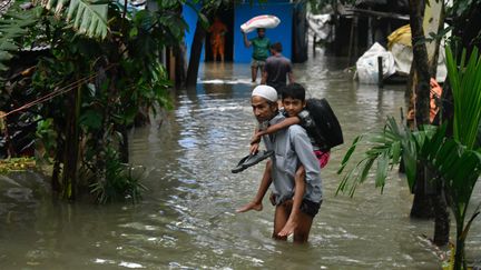 Des habitants de Feni, au Bangladesh, dans une rue inondée, le 23 août 2024. (SYED MAHAMUDUR RAHMAN / NURPHOTO / AFP)