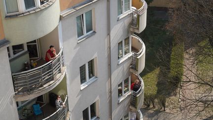 Des habitants confinés profitent du soleil à leur balcon, le 28 mars 2020, à Varsovie. (JANEK SKARZYNSKI / AFP)