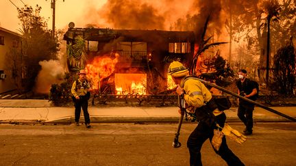 Des pompiers tentent d'éteindre un incendie qui ravage une maison, le 8 janvier 2025 à Altadena, au nord de Los Angeles (Californie), aux Etats-Unis. (JOSH EDELSON / AFP)