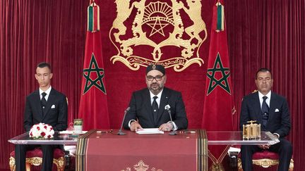 Le roi du Maroc,&nbsp;Mohammed VI, lors d'un discours le 20 août 2019, entouré par son fils le prince Moulay Hassan à sa droite et son frère le prince Moulay Rachid à sa gauche. (- / MAP / AFP)