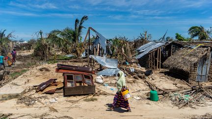 Une femme marche devant une maison détruite par le cyclone Kenneth, sur l'île d'Ibo au Mozambique, le 13 mai 2019.&nbsp; (ZINYANGE AUNTONY / AFP)