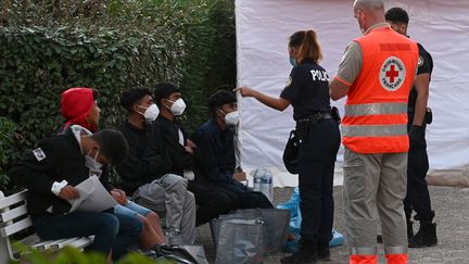 Une policière discute avec des migrants dans la zone d'attente fermée de Hyères (Var), le 11 novembre 2022. (CHRISTOPHE SIMON / AFP)